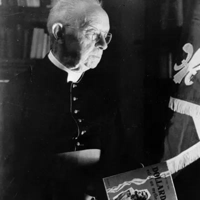 Lionel Groulx tenant son ouvrage « Dollard est-il un mythe? », dans le bureau de sa résidence d'Outremont, vers 1960.