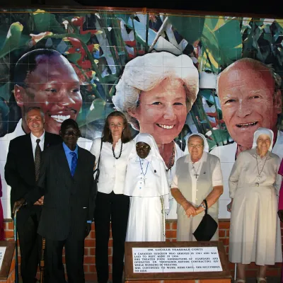 Photo prise en 2009 à l’occasion du 50e anniversaire de l’hôpital St. Mary’s Lacor, devant une murale dédiée à Matthew Lukwiya, Lucille Teasdale et Piero Corti